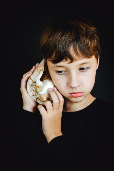 Enfant qui écoute la mer dans un coquillage Enfant qui écoute la mer dans un coquillage